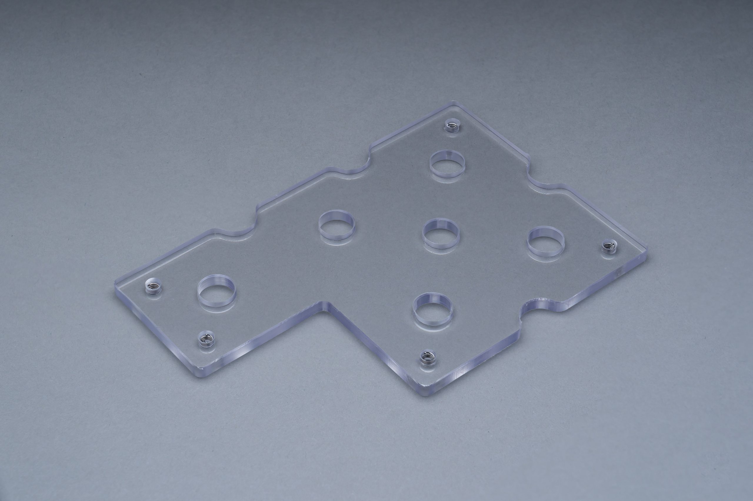 A clear resin sample part with threaded inserts